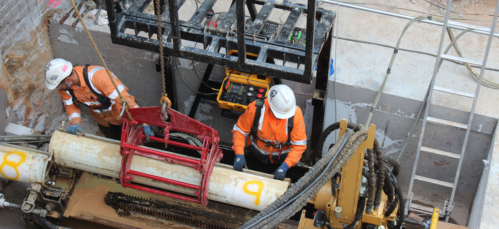Two workers guiding a pipe string in a shaft